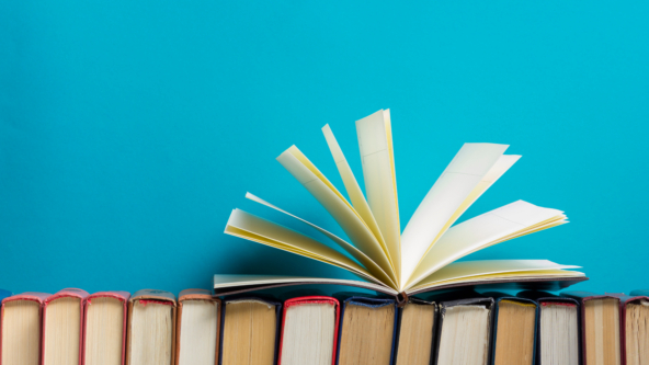 An open book sat on top of other books lined up